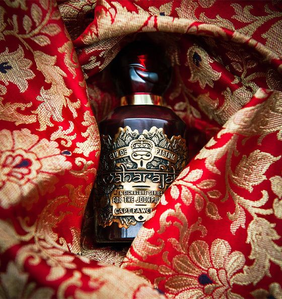 Eau de Parfum Maharajah von Captain Fawcett in edlem Flakon auf rotem, goldverziertem Stoff, intensiv und opulent mit Rosen-, Gewürz- und Holzduft.