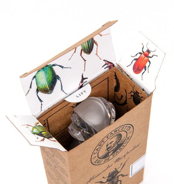 Offenes Verpackungskarton mit Eau de Parfum Manfredini Flakon von Captain Fawcett und illustrativen Käfermotiven innen.