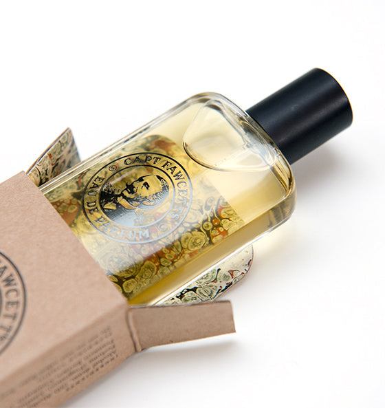 Eau de Parfum Private Stock Captain Fawcett in eleganter Glasflasche mit schwarzem Verschluss neben brauner Verpackung, abenteuerlicher und geheimnisvoller Herrenduft mit Bergamotte, Kardamom und Vanille.