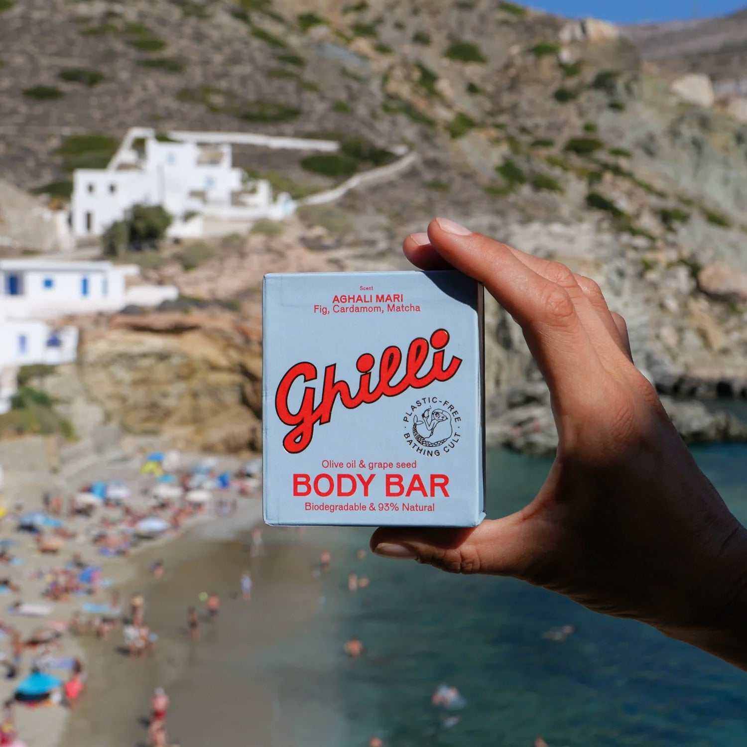 Hand hält Ghilli Body Bar Aghali Mari mit Olivenöl und Traubenkernen am Mittelmeerstrand in der Sonne