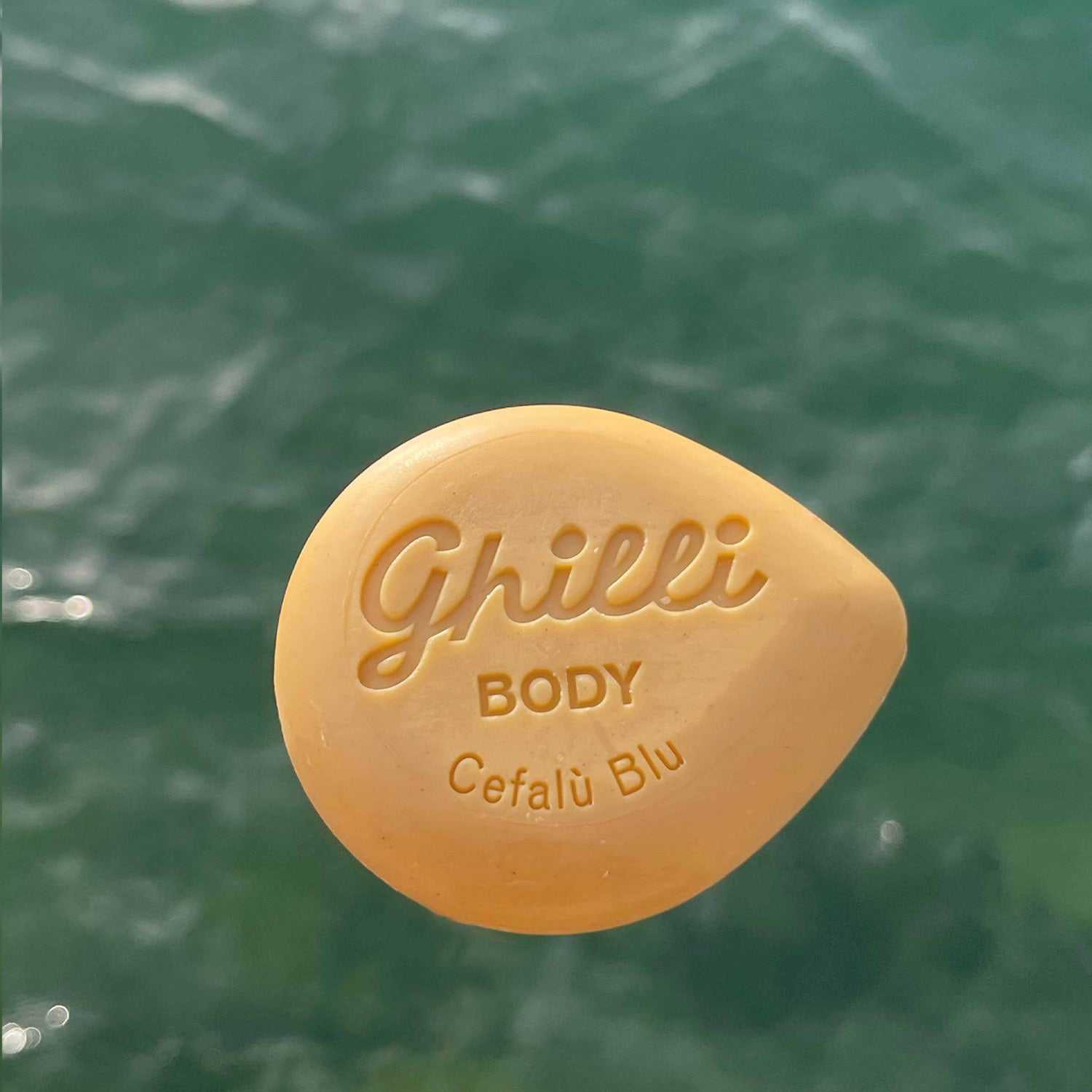 Body Bar Cefalù Blu von Ghilli beige Körperseife mit mediterranem Duft und Peelingwirkung vor Wasseroberfläche