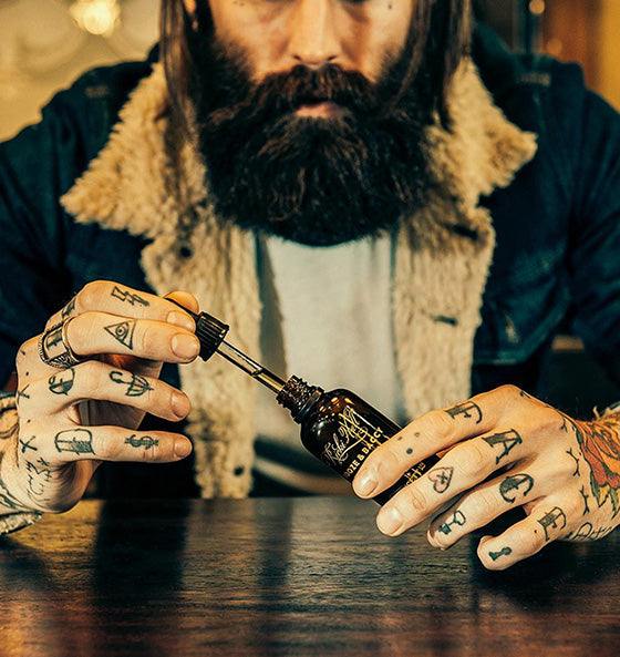 Mann trägt Bartöl Booze & Baccy von Ricki Hall - Captain Fawcett auf, pflegt Bart mit Duft von Tabak, Vanille und Holznoten.