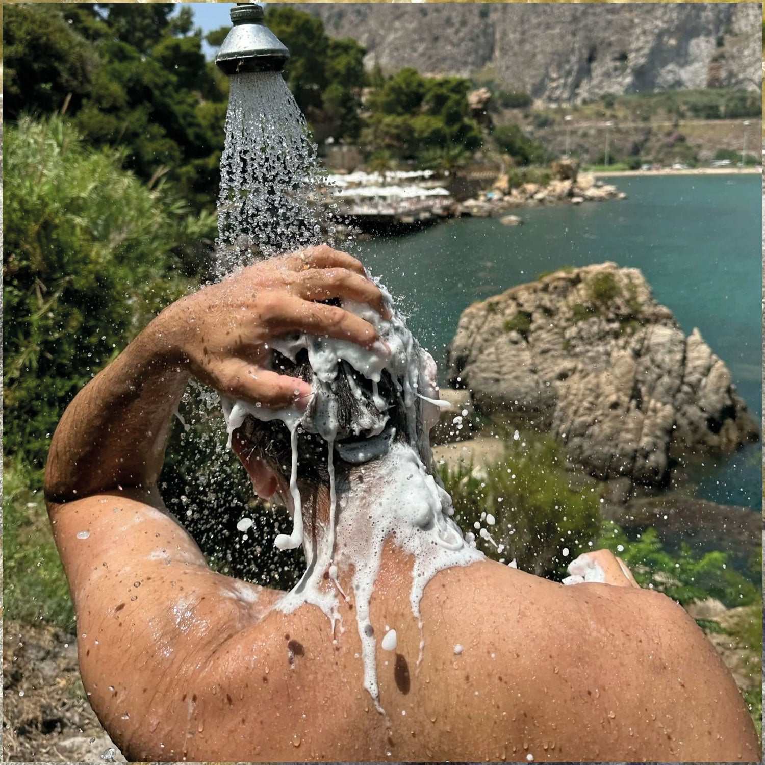 Person wäscht Haare draußen mit Shampoo Bar Plage Paloma - Ghilli unter Wasserfall