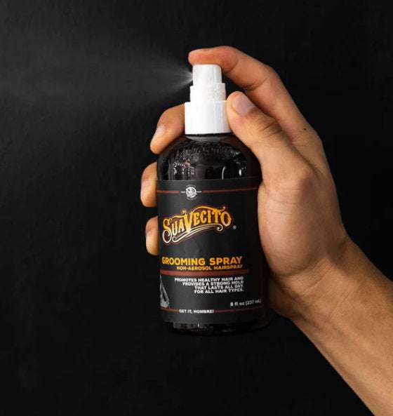Hand hält Suavecito Grooming Spray für kontrolliertes und glänzendes Haar ohne Aerosol