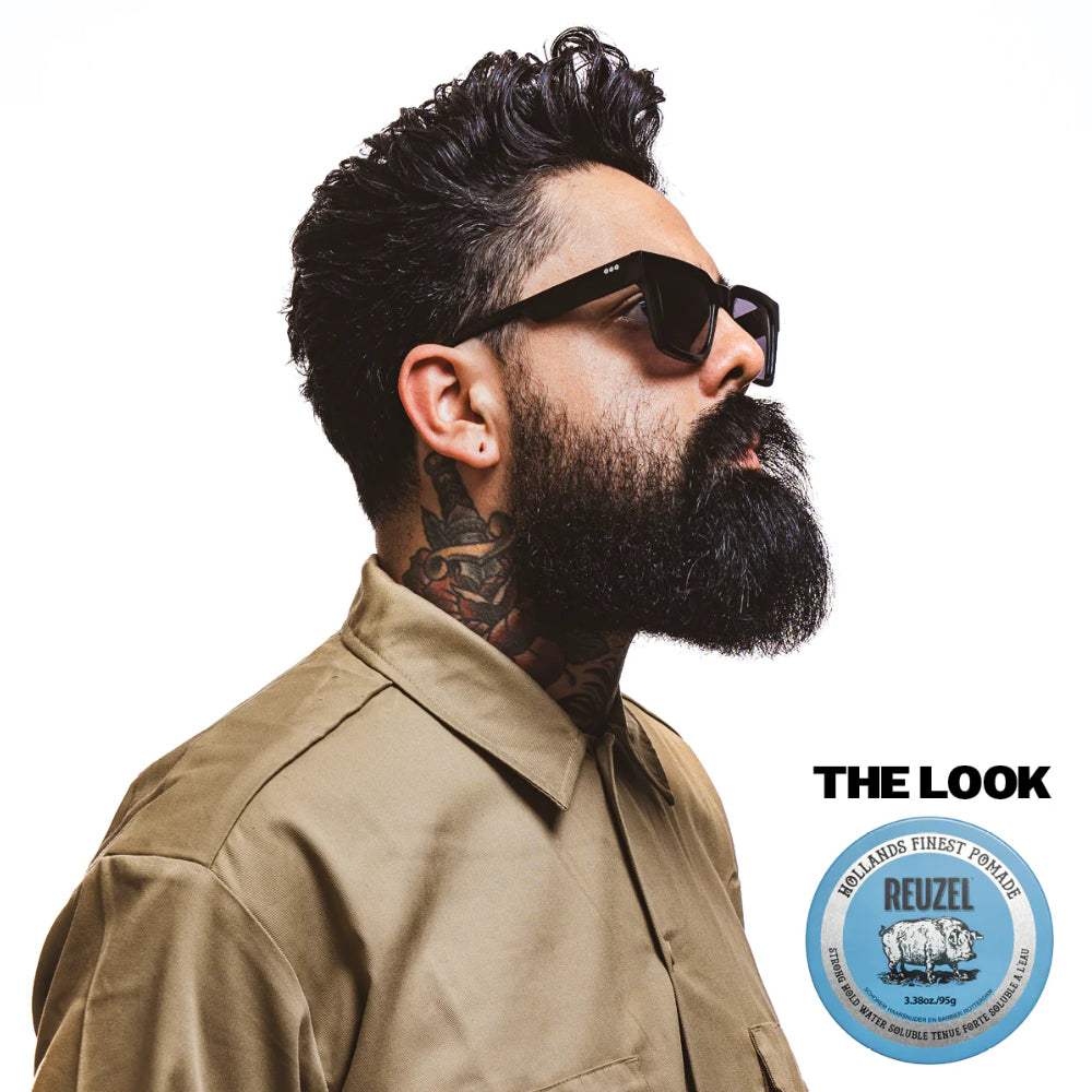 Mann mit dichtem Bart und stylischem Volumen im Haar, gehalten mit Haarpomade blue strong hold Pomade - Reuzel, für starken Halt und glänzendes Finish.